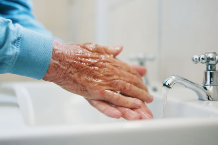 persona mayor lavandose las manos